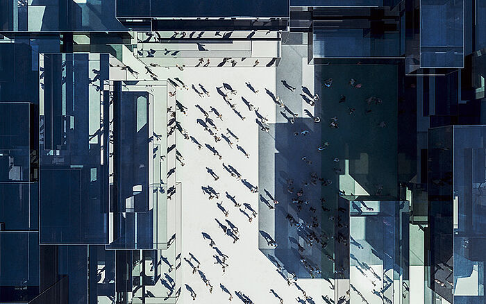 High-angle view of people walking to work in modern glass-fronted office buildings.