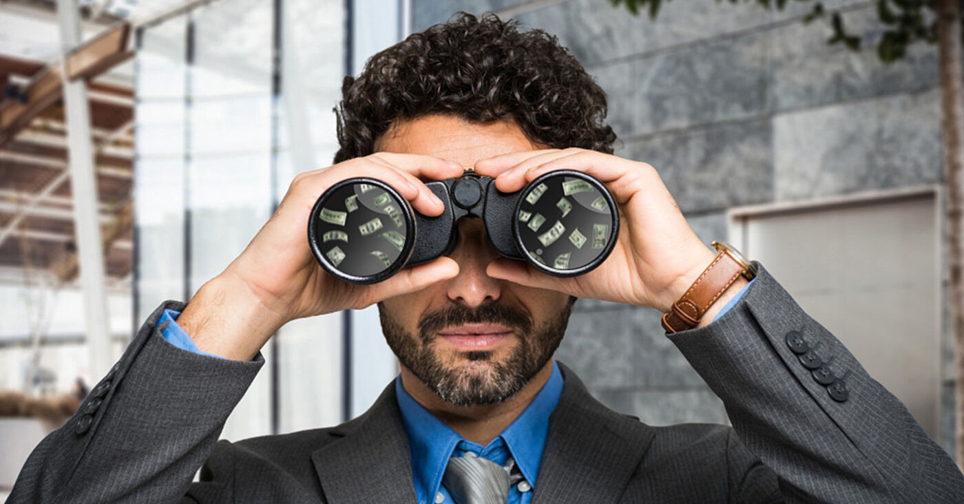 Businessman looking through binoculars with money reflected in the lenses, symbolizing financial foresight or opportunity scanning.