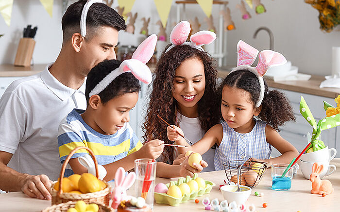 Parents and children painting Easter eggs at the kitchen table, reflecting shared seasonal traditions