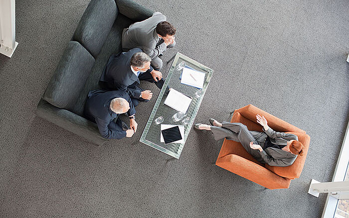 A panel of three men interviews a woman for an important task.