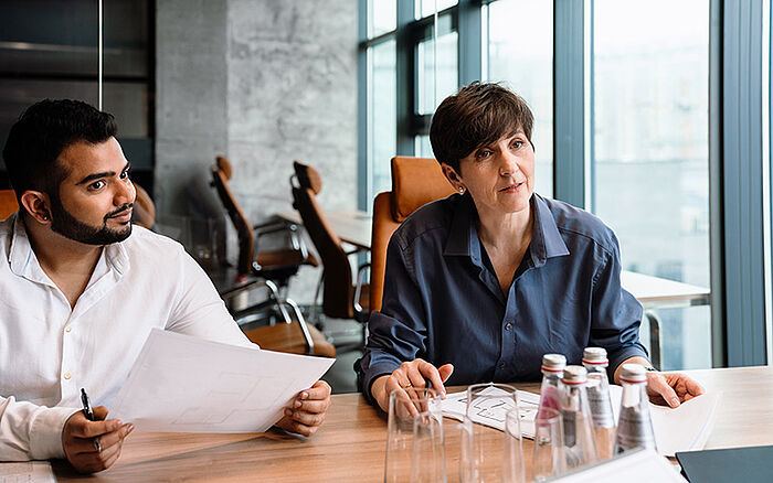 Team members discussing paperwork and project details in a collaborative workspace.