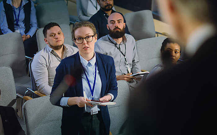 Close-up of a public figure speaking at a podium in a conference hall.