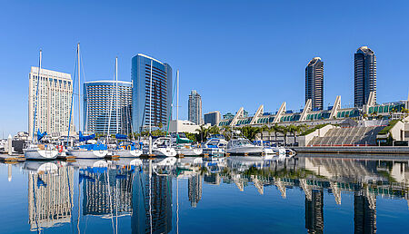 Panoramic morning view of San Diego Marina, with yachts docked along the bay and modern high-rise buildings in the Marina District of downtown San Diego, California.