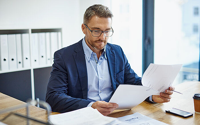 Business man sitting at his desk, reviewing a trademark application. 