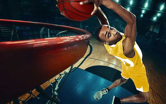 Close-up shot of a man about to complete a reverse dunk.