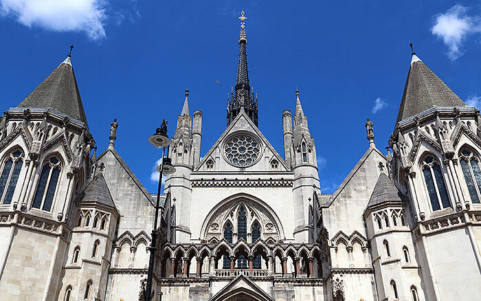 Exterior of the Royal Courts of Justice in London, showing the Gothic-style facade with pointed arches, tall spires, and detailed stonework along the Strand. [alamy.com]