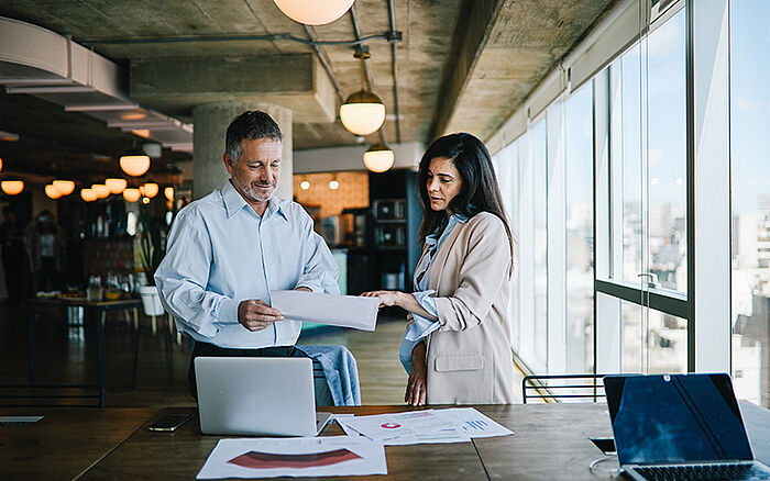 Colleagues collaborating at a desk in a modern office, focused on shared work.